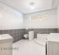 Bathroom in a family house with a bathtub, sink, toilet, and washing machine.