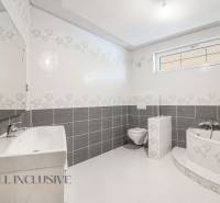 Bathroom with a bathtub, toilet, and sink in a family house, bright and simple design.