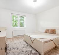 A bright bedroom with a bed, television, and window in a family house.