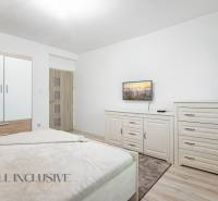 Bright bedroom with a bed, wardrobe, dresser, and television in a family house.