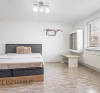 Bright bedroom in a family house with a bed, shelf, and large window.