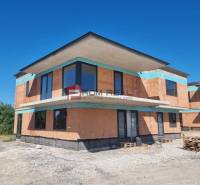 The exterior of an under-construction 3-room apartment in Dubová with brick walls and large windows.