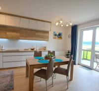 Studio apartment with a bright kitchen, dining table, and a view from the balcony doors.