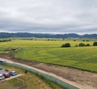 View from a studio apartment on Suchoňova Street in Poprad, with a field and cars.