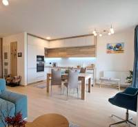 Studio apartment with a comfortable sofa, dining table, and kitchenette with wooden details.