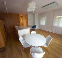 A kitchen with an island and a dining table in a family house, light walls and wooden floors.