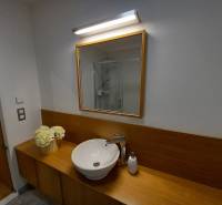 A bathroom in a family house with a sink, mirror, and decorative flowers.