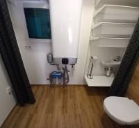 A bathroom in a family house with a boiler, sink, toilet, and practical storage solution.