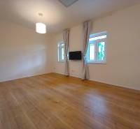 A spacious room with wooden flooring and a television in a family house.