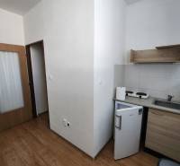 Kitchen in a building with a floor, doors, and small appliances, including a refrigerator and a stove.