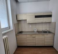 Kitchen unit in a building with a window, cabinets, and a cooktop.