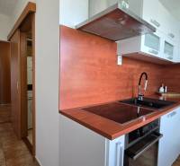 A kitchen in a 2-room apartment with built-in appliances and modern cabinets.