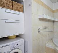 Bathroom with a washing machine and storage baskets in a 2-room apartment.