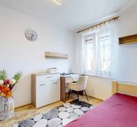 A bedroom with a bed, wardrobe, and desk, decorated with flowers, in a two-room apartment.