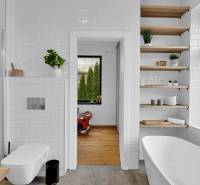 A bathroom in a family house with a bathtub, shower, and open shelves.