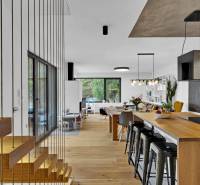 Staircase and open kitchen with an island and bar stools in a family house.