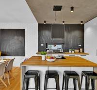 A kitchen in a family house with a dining table, bar stools, and appliances.