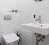 A small bathroom in a family house with white tiles, a sink, and a toilet.