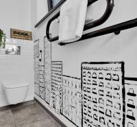 Bathroom with toilet in a family house, tiled walls and graphic wall decor.