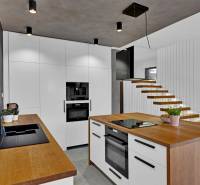 A kitchen in a family house with modern furniture and a minimalist staircase design.