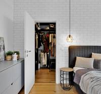 Bedroom of a family house with an open wardrobe, bed, and decorations on the dresser.