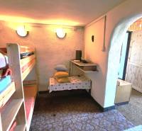 Interior of a cabin with a bunk bed, a small table, and cushions on a shelf.