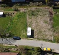 Aerial view of a street with a plot of land, a utility building, and two cars, ideal for living.