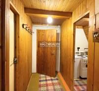 A wooden interior of a cabin with coat hooks and a kitchen on the right.