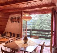 Interior of a cabin with wooden paneling, a dining table, and a view of the forest.
