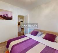 A bedroom in a 3-room apartment with purple accessories and a painting on the wall.