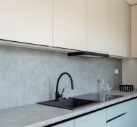 A kitchen in a 2-room apartment with a simple countertop and a black faucet.