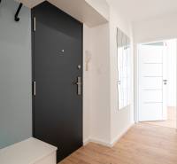 Hallway in a 2-room apartment, light walls, wooden floor, mirror, and doors.