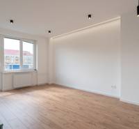 A bright room in a 2-room apartment with laminate flooring and large windows.
