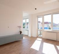 Living room of a two-room apartment with wooden flooring and large windows.