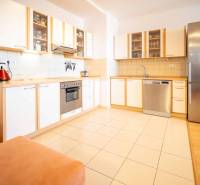 A kitchen with a wooden cabinet, a stove, and a silver refrigerator in a three-room apartment.