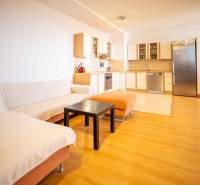 Living room with kitchen in a 3-room apartment, wooden floor and built-in kitchen unit.