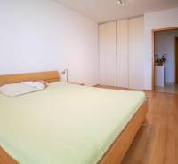 Bedroom in a 3-room apartment with a wooden bed and wardrobe, light wooden floors.