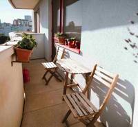 A balcony of a 3-room apartment with wooden furniture and flower pots.