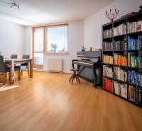 Living room with a piano, bookshelf, table, and chairs in a 3-room apartment.