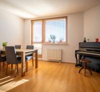 A bright room in a 3-room apartment with a piano and a dining table.