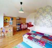 Children's room in a cabin with wooden paneling, colorful blanket, and floral wallpaper.