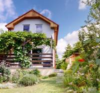 A cottage in Stupava with rich greenery and blooming flowers in the garden.