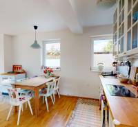 A bright kitchen in a cottage with wooden furniture, modern equipment, and access to a terrace.