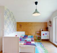A room in a cottage with floral motifs, a bed, and a large window for pleasant lighting.