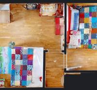 A room in a cottage with two colored beds and a wooden floor.