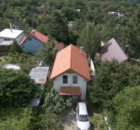 A cottage in Stupava surrounded by greenery with a view of the surrounding hills.