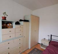 A room in a family house with furniture, a carpet, a bed, and decorations.