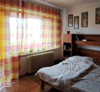 Bedroom in a family house with curtains, paintings, and a radiator.