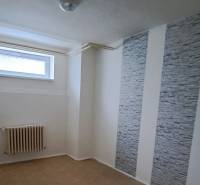 A room in a family house with a radiator, gray walls, and a small window.