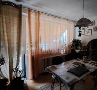 Dining area in a family house with curtains, decorations, and a table with chairs.